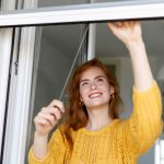 Woman hand hold retractable pleated insect screen holder to open or close the window ,mosquito nets