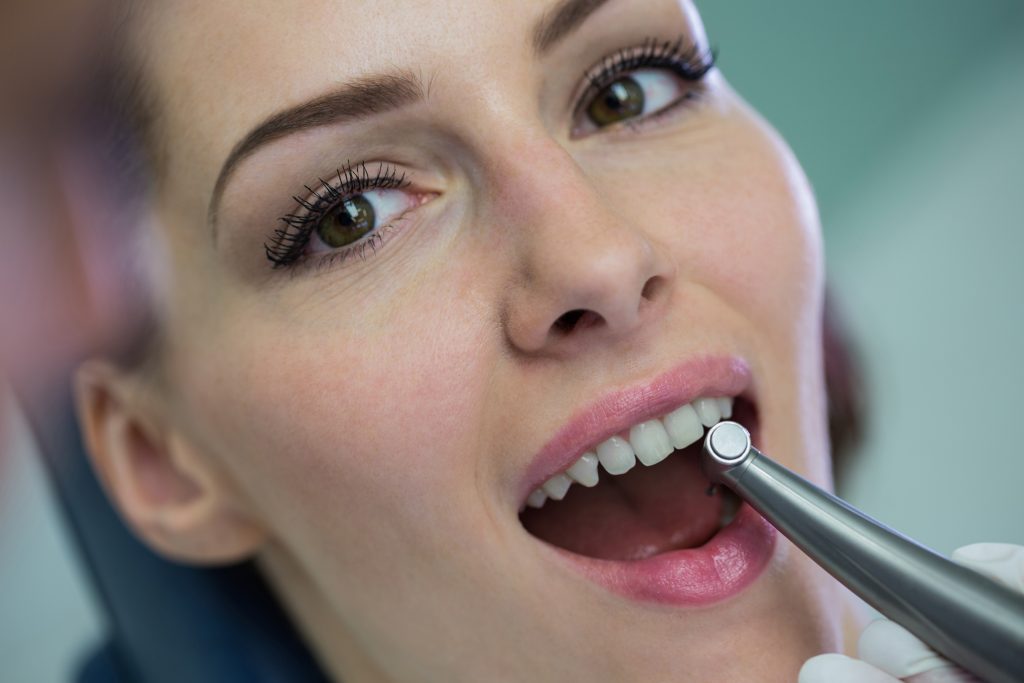 Dentist examining a female patient with tools at dental clinic