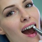 Dentist examining a female patient with tools at dental clinic