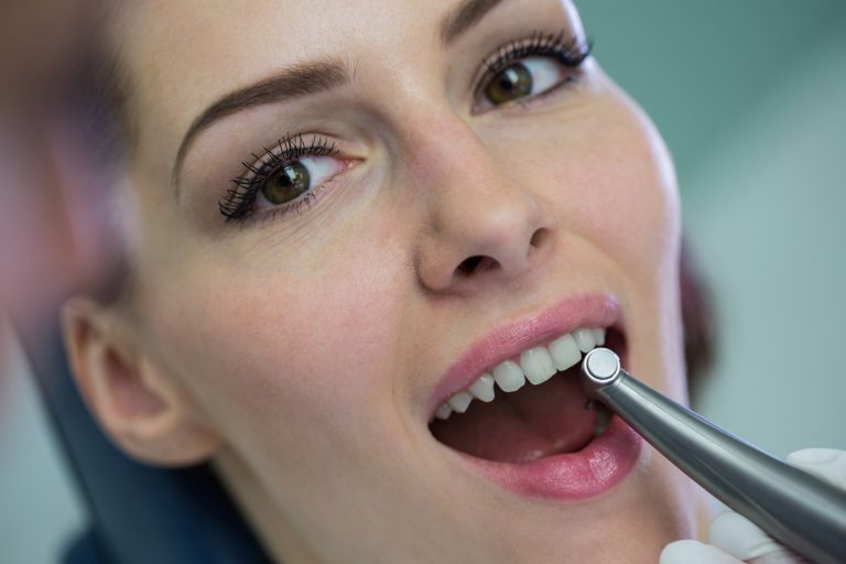 Dentist examining a female patient with tools at dental clinic
